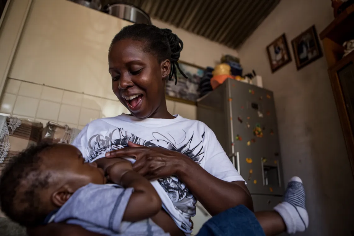 A young woman stands while breastfeeding her son.