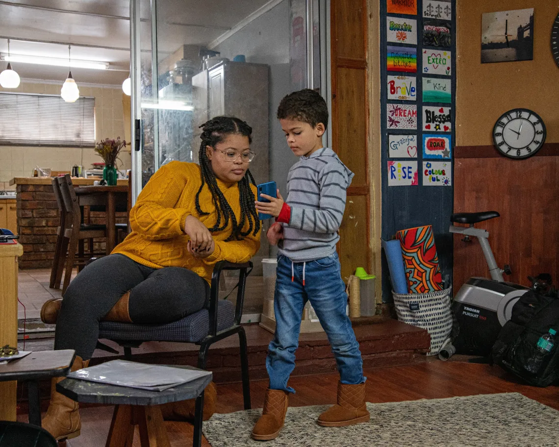 Eleanor (38) looks at ten-year-old Aidan&rsquo;s phone at their home in Kriega, Eastern Cape.