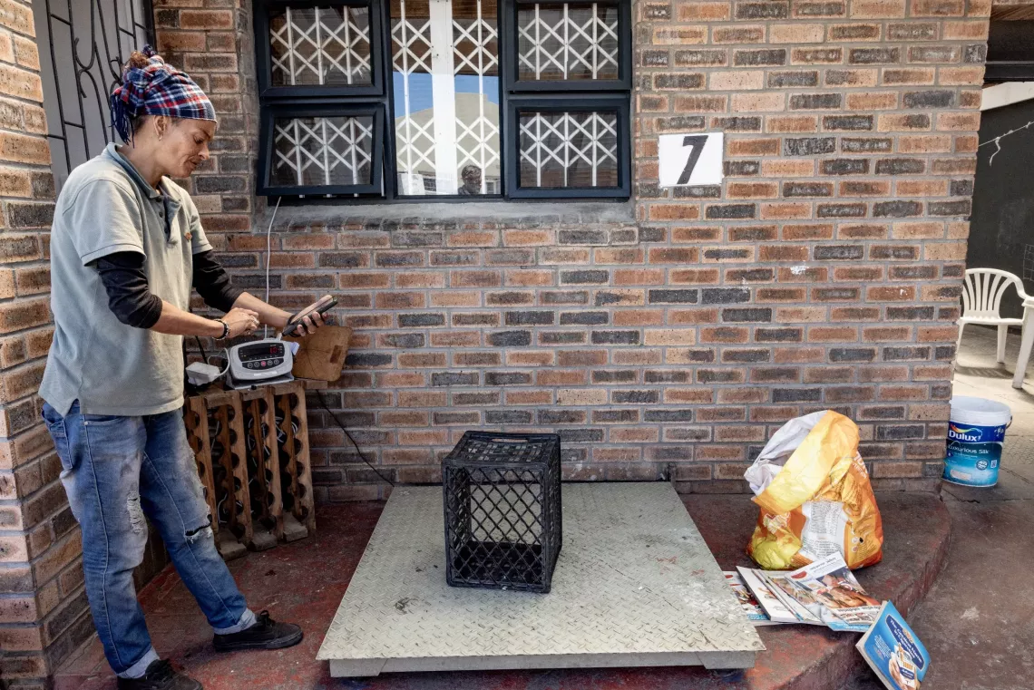 A woman looks at an app on her phone where she records the weight of the waste dropped off.