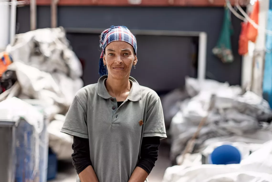A woman smiles proudly outside a waste drop-off point.