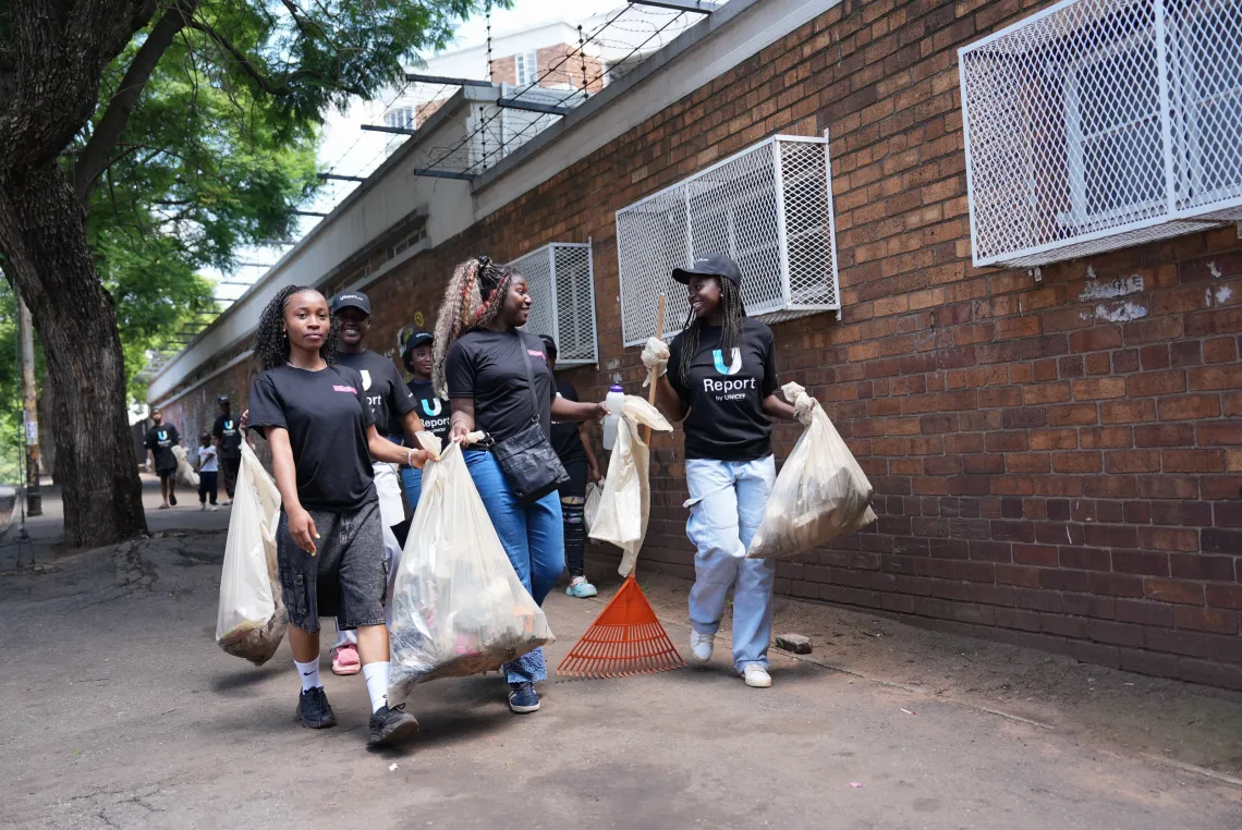 Young women carrying bags filled with rubbish that they have cleaned from the street.
