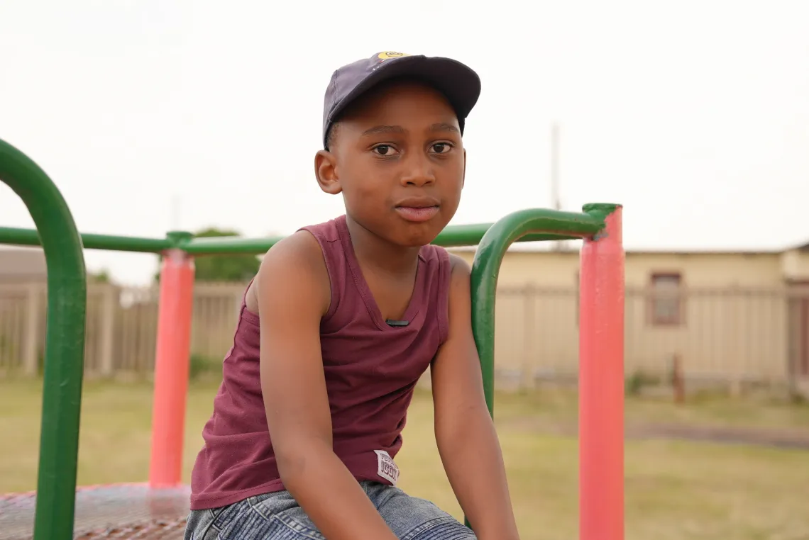  A young boy sits on playground equipment.