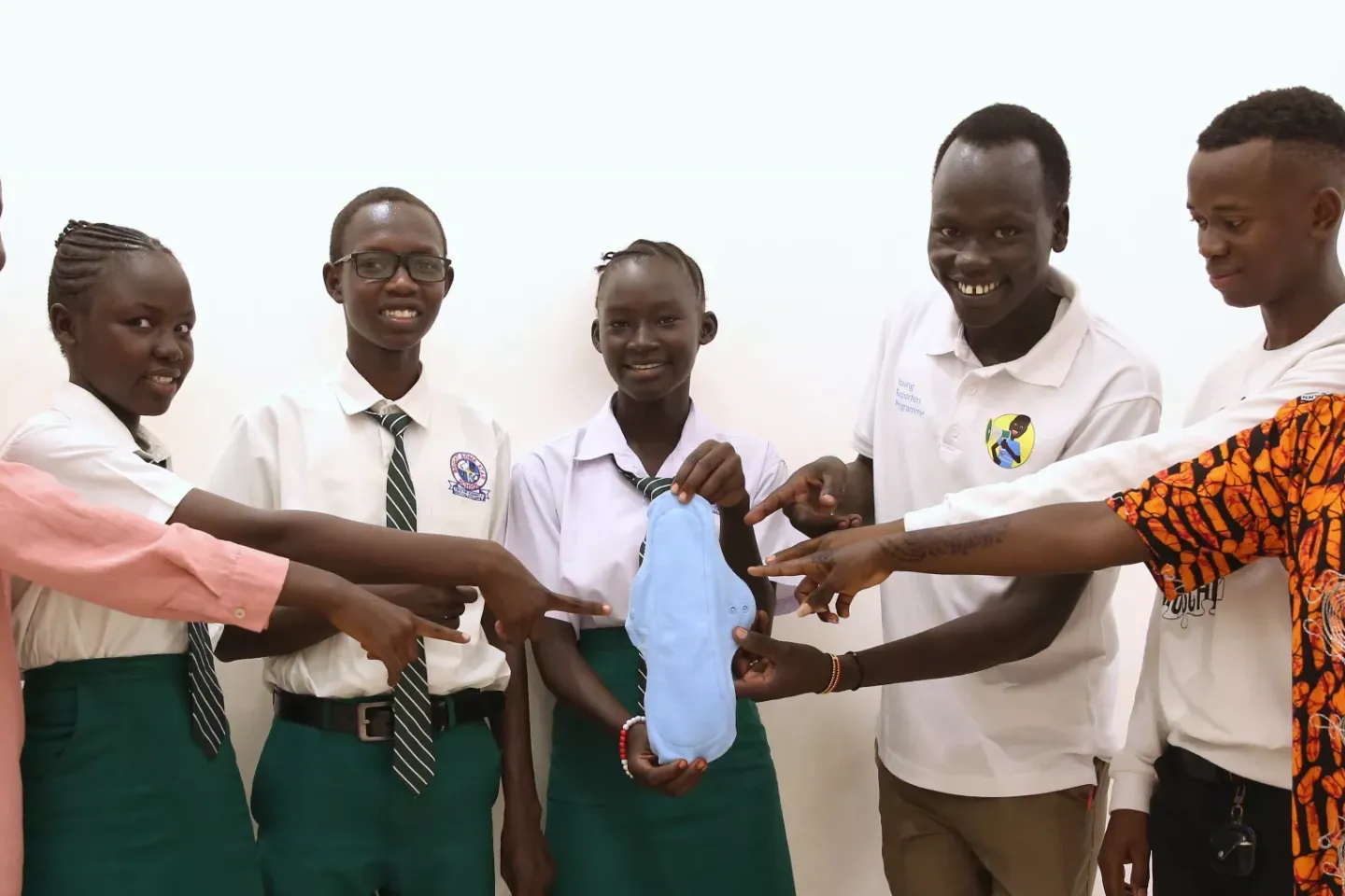 UNICEF young reporters are photographed pointing at a sanitary pad in Juba, South Sudan