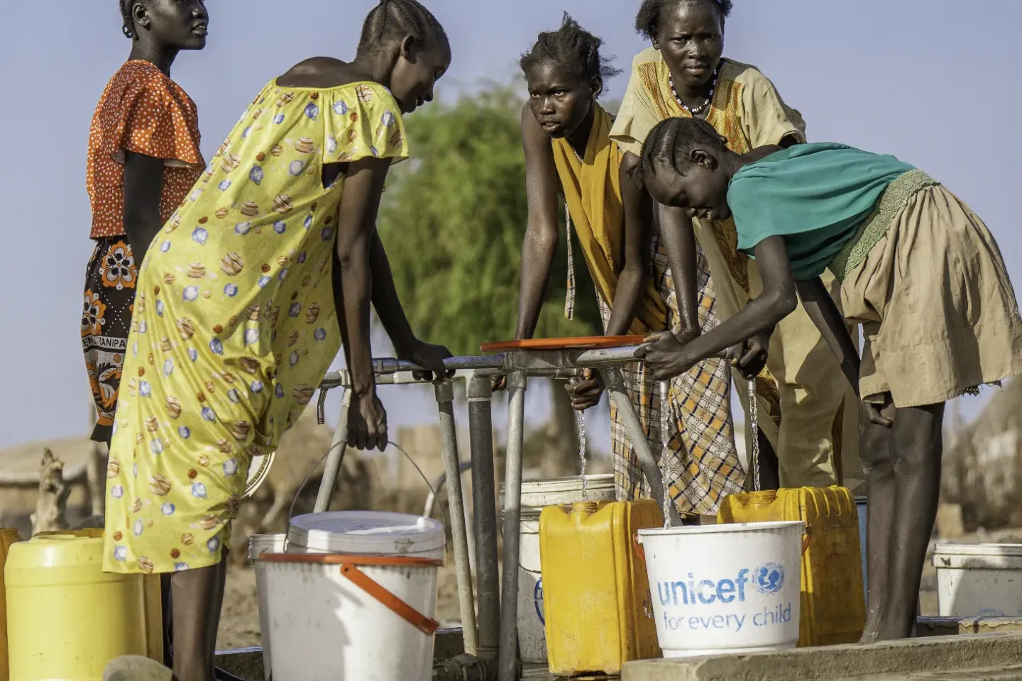 young girls and mother at a water point to collect water