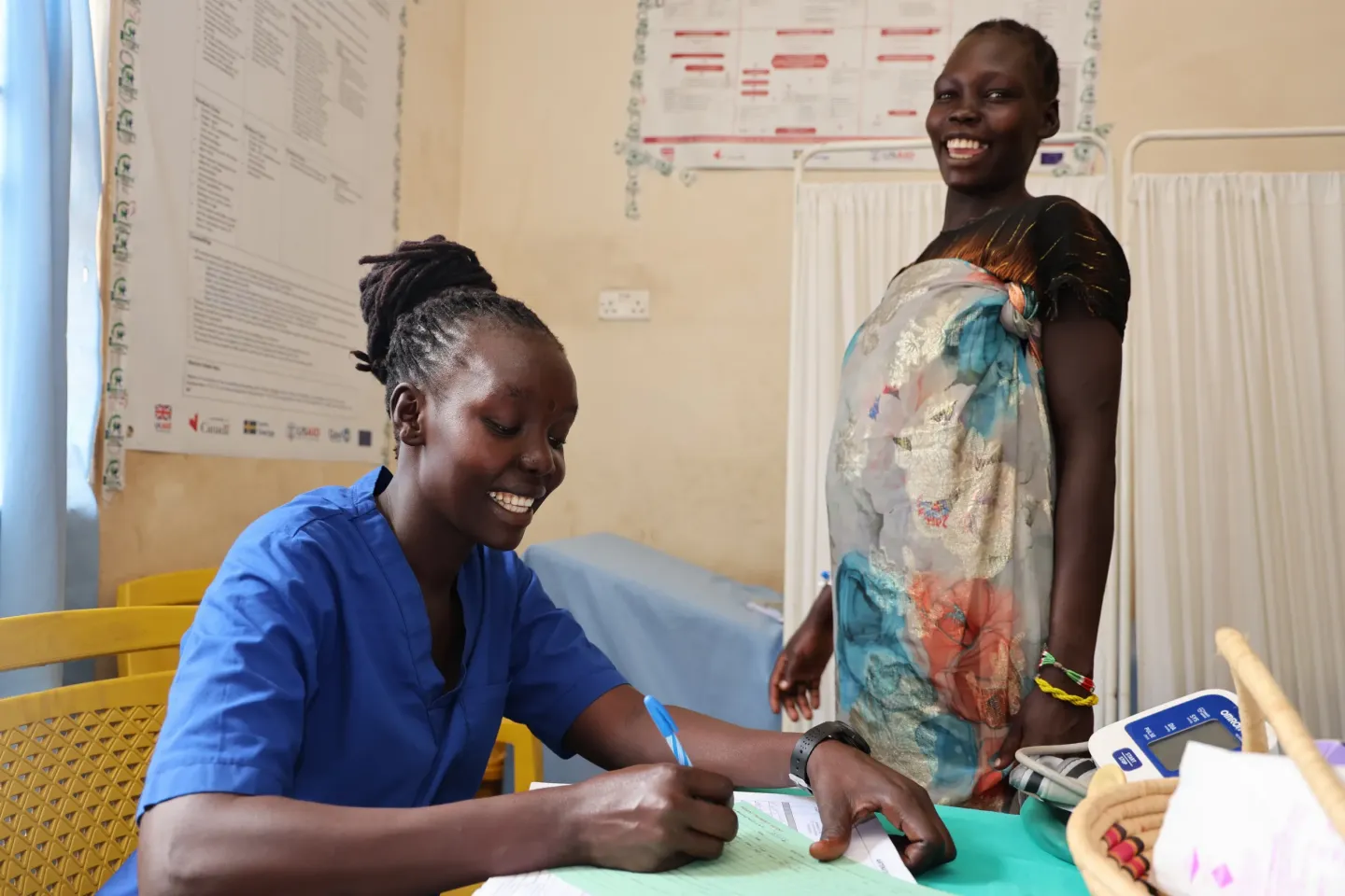 Monday Ousman is sitting in her office and writing while a midwife is standing next to her in Bor, south Sudan