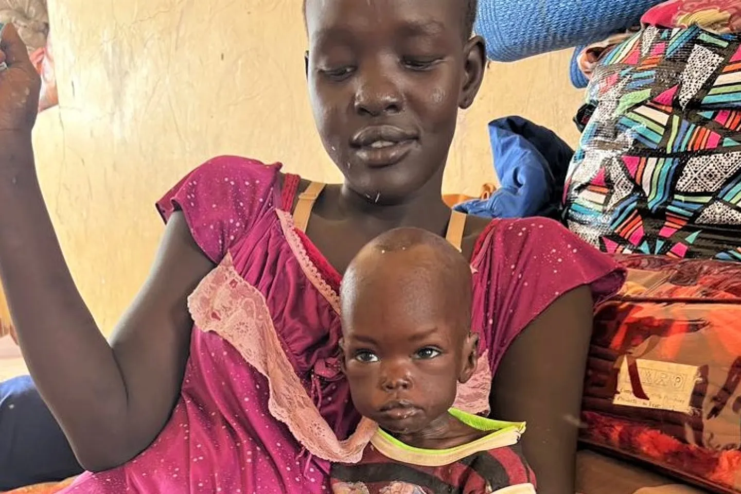 Mother holding her baby girl Kamisa who is suffering from severe acute malnutrition. Renk South Sudan, 2023