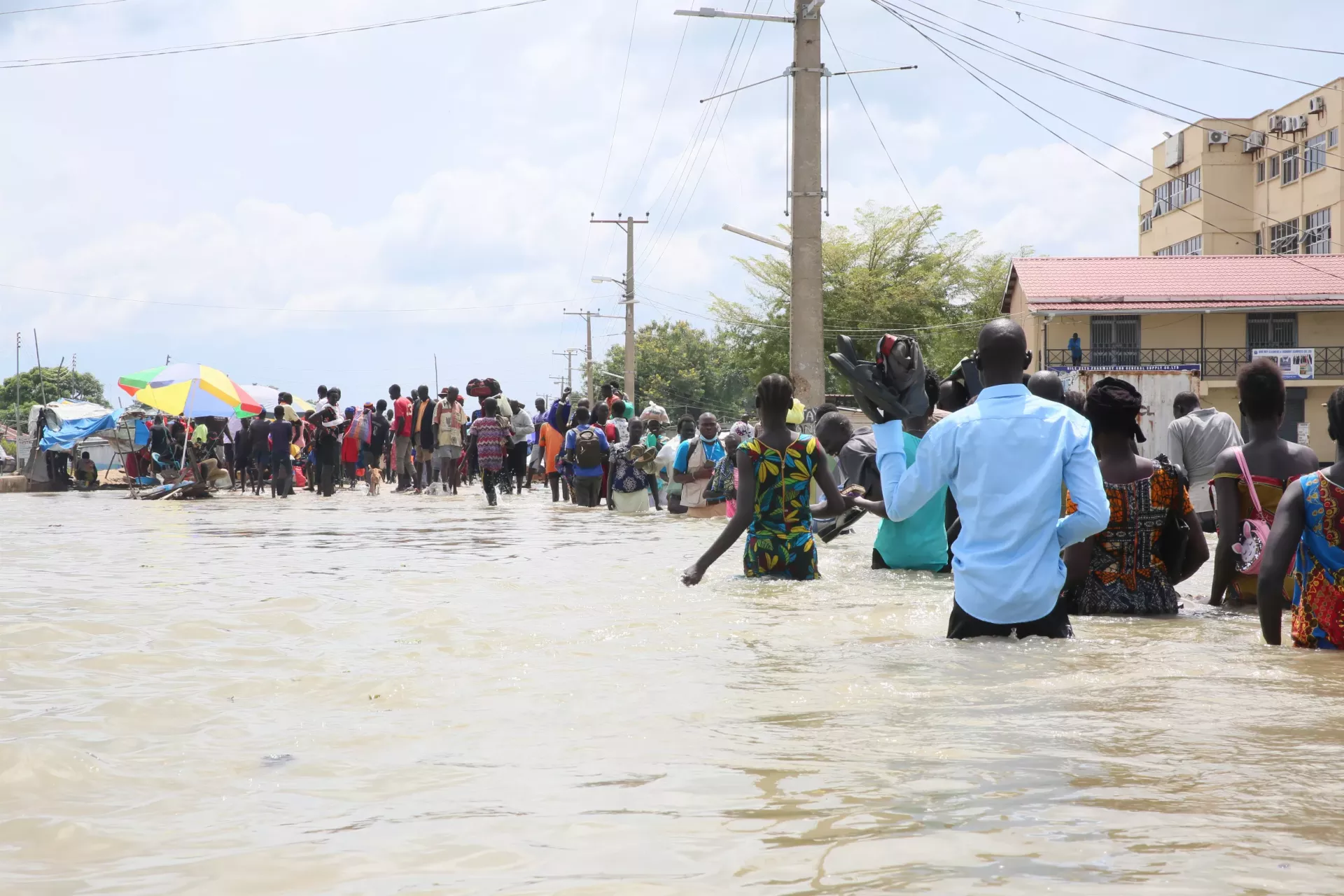 Men, women, children walking through water in flooded area, Bor, South Sudan