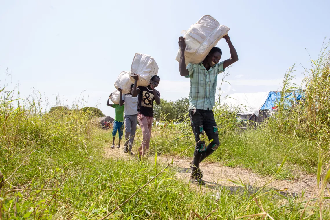 Men carrying mosquito nets packages on their shoulders