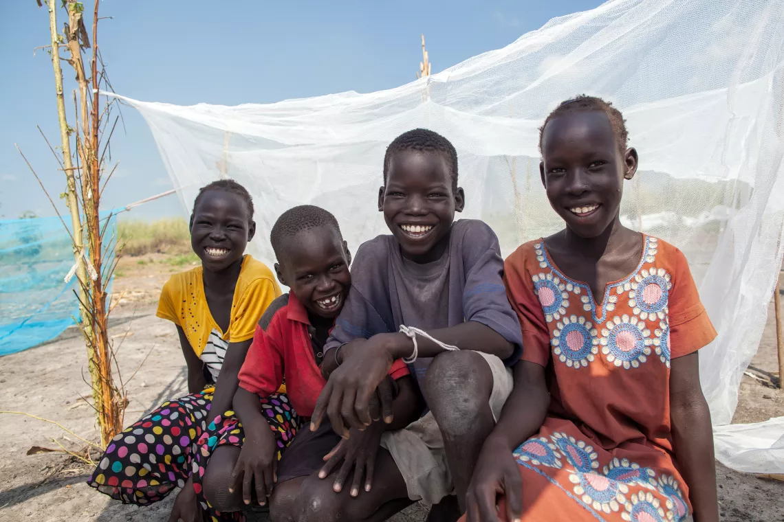 Children sitting in front of a mosquito net