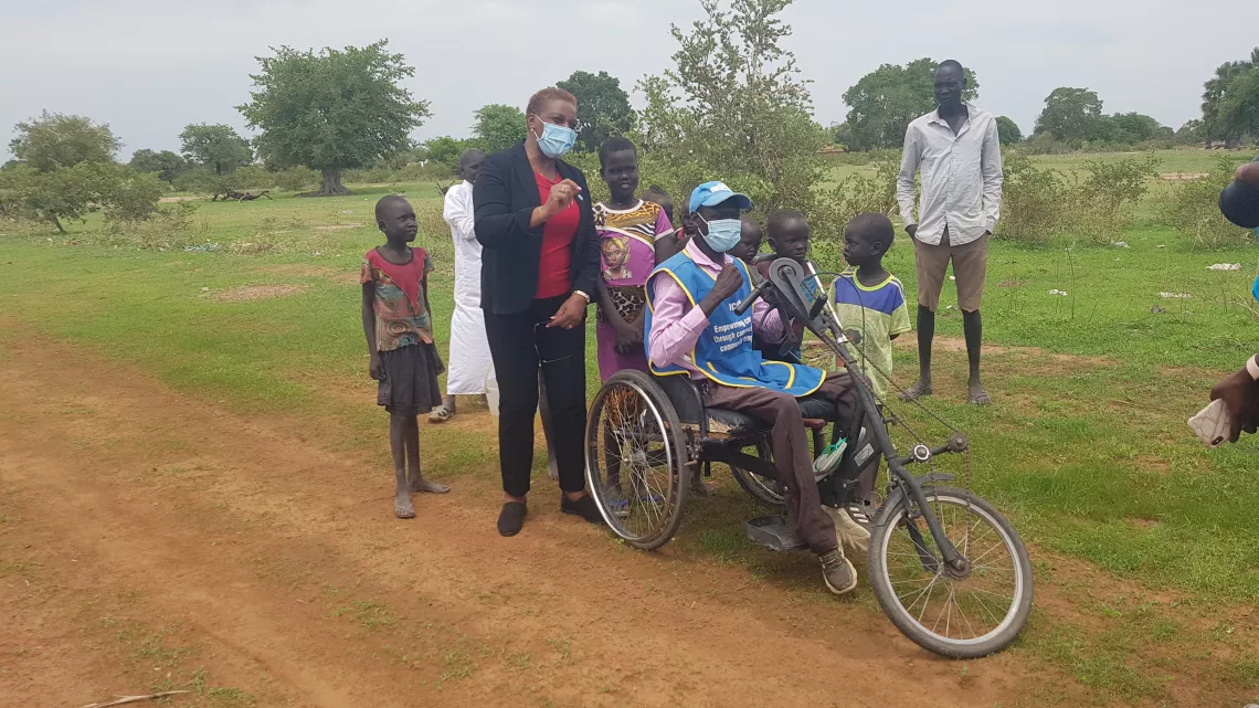 A man hand-wheeling himself surrounded by people
