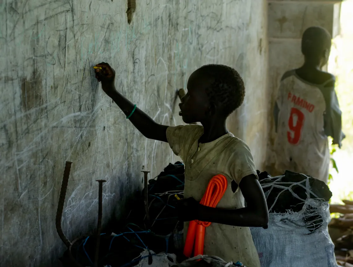 Missing her school days, a young girl writes her ABC's on the wall of the abandoned building she lives in.