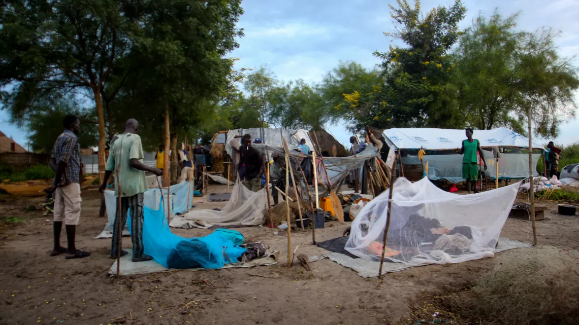People displaced by floods sleep out in the open, some have mosquito nets.
