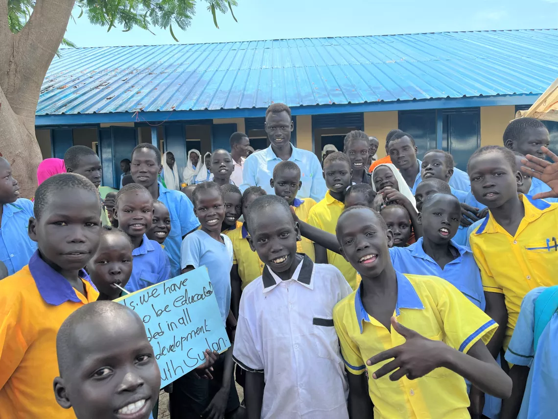 Schoolchildren stand proudly beside the new school with their teacher. 
