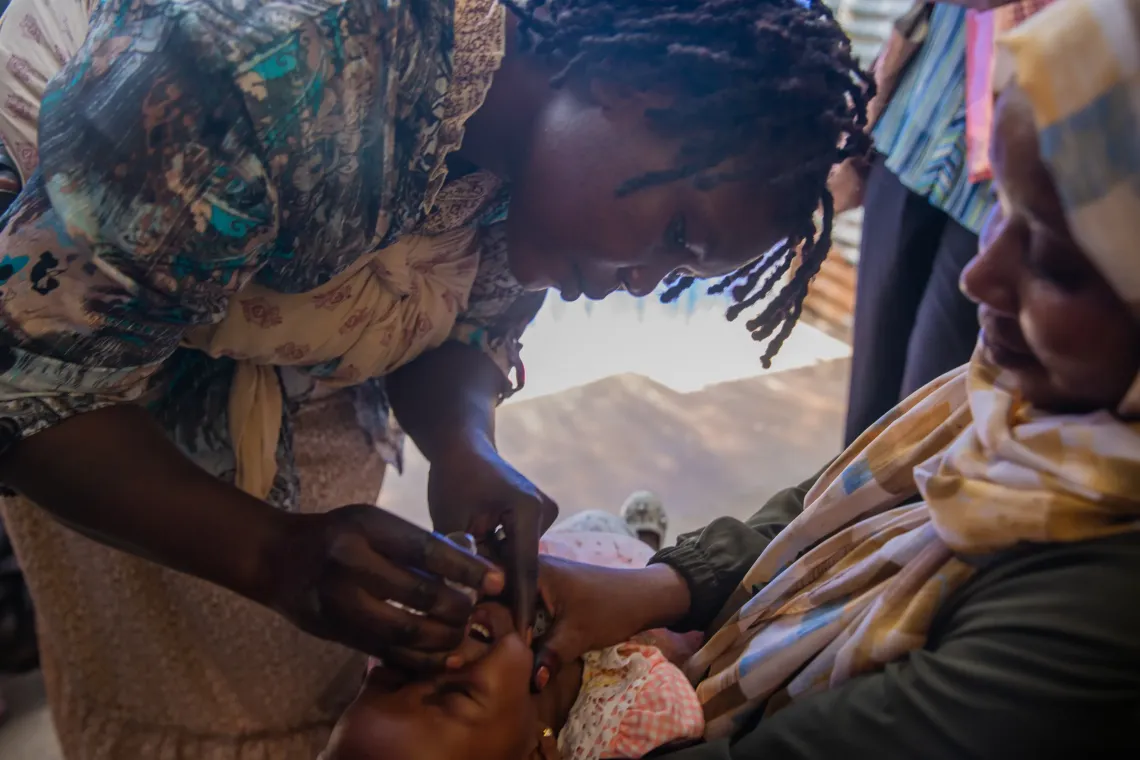 Linda Patrick, a polio vaccinator administers oral polio vaccine to a child 