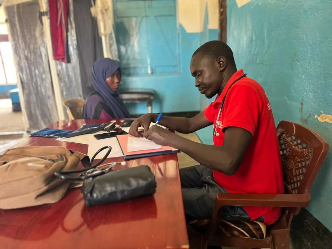 Doctor at the hospital prescribing medicine to a mother, Renk, South Sudan