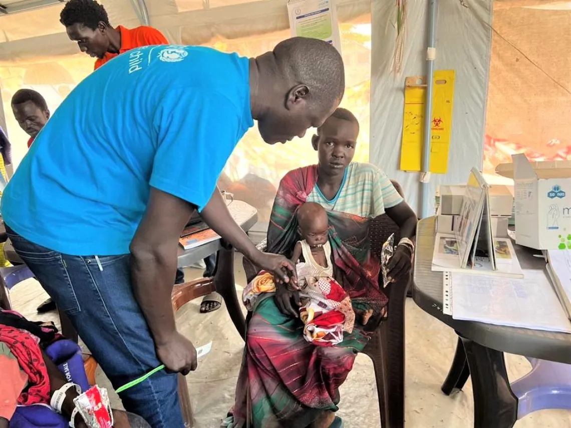 Otto Stephen, a nutrition worker advising Yumjima on nutrition for her child.