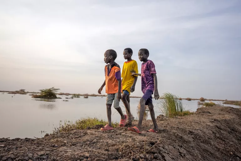 On 27th February 2023, boys walk past flooded fields in Bentiu, Unity State, South Sudan. Extensive flooding has affected thousands of people across Unity State with many having to flee their homes.