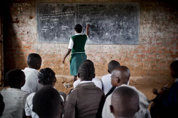 A girl is writing on a blackboard in a classroom