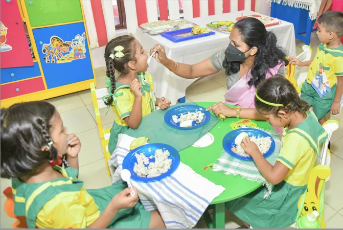 preshool teacher feeding a child