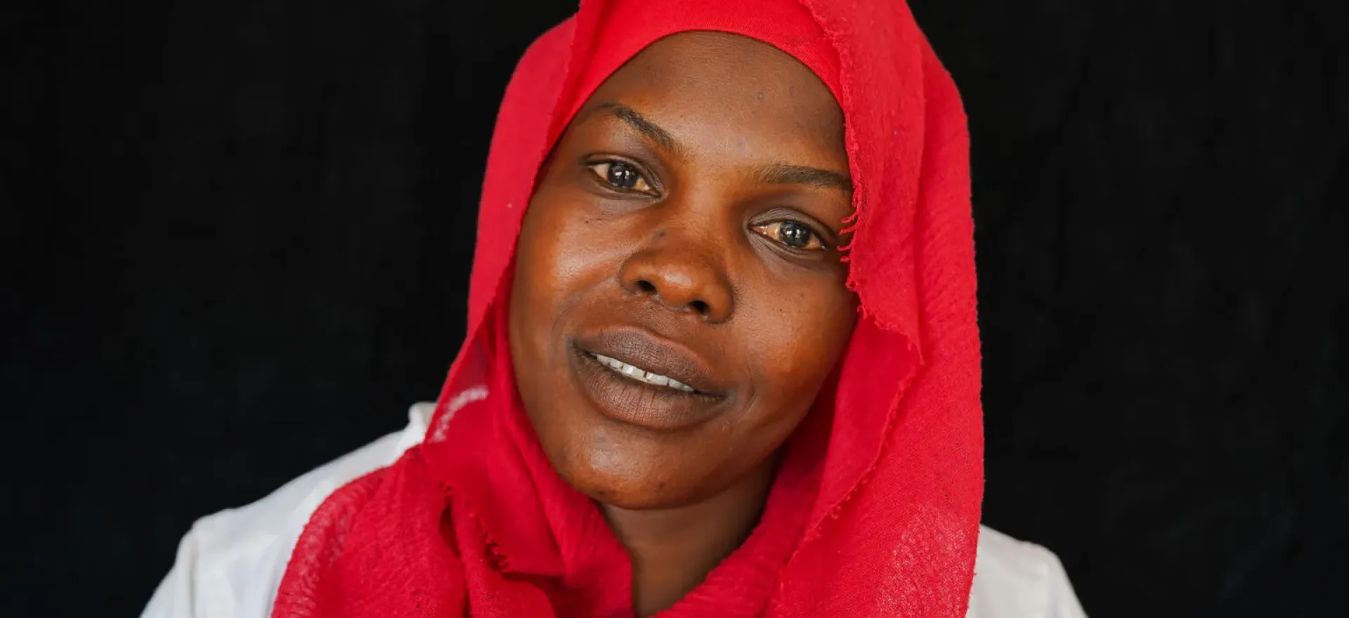 Sudan. Fadeela, who is wearing a red headscarf, smiles at the camera.