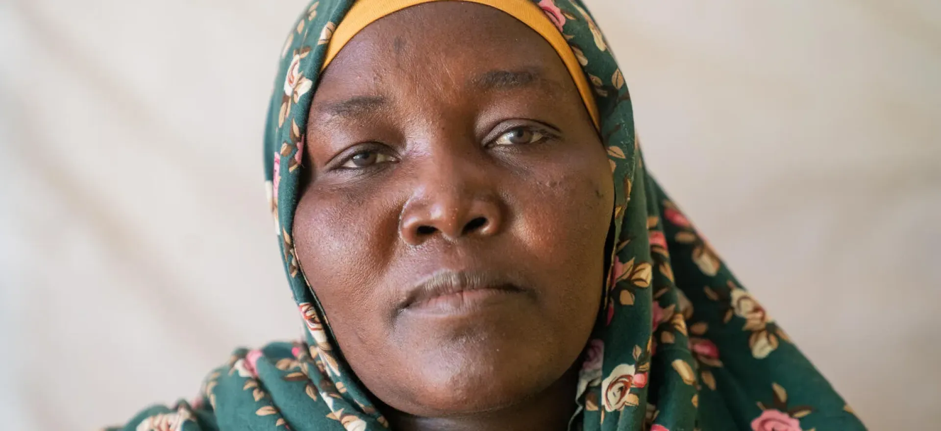 Sudan.  Amina, wearing a green headscarf, looks toward the camera at a UNICEF-supported health facility in Tawila.