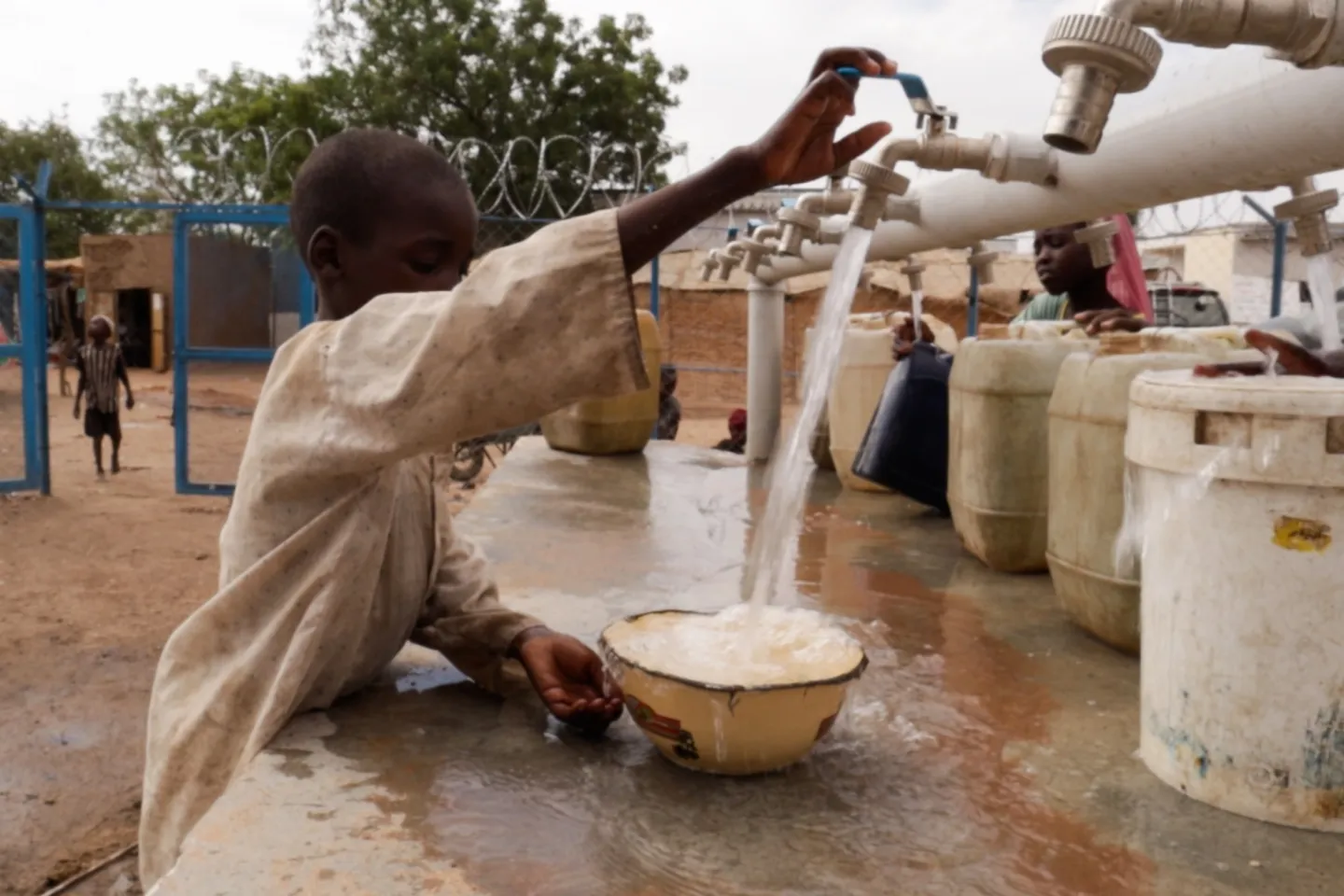 A child opens a tap for clean and water into a bowl.