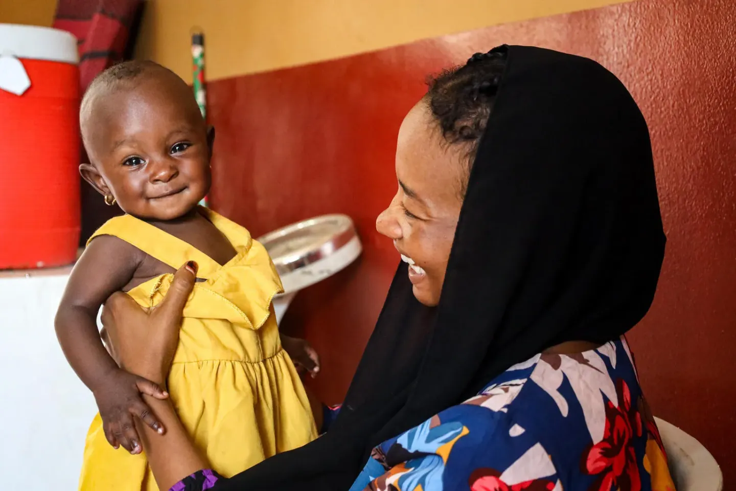 A mother enjoys a light moment with her child as she awaits services at a heath facility in Nyala.
