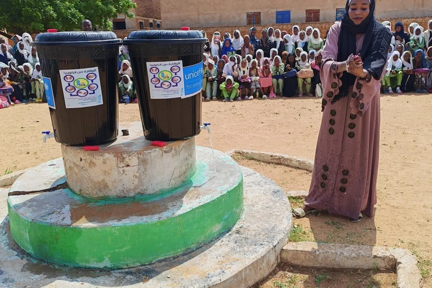 Teacher Firdous demonstrates how to wash hands with water and soap during a morning assembly at Uhud Basic School, Nyala, South Darfur.