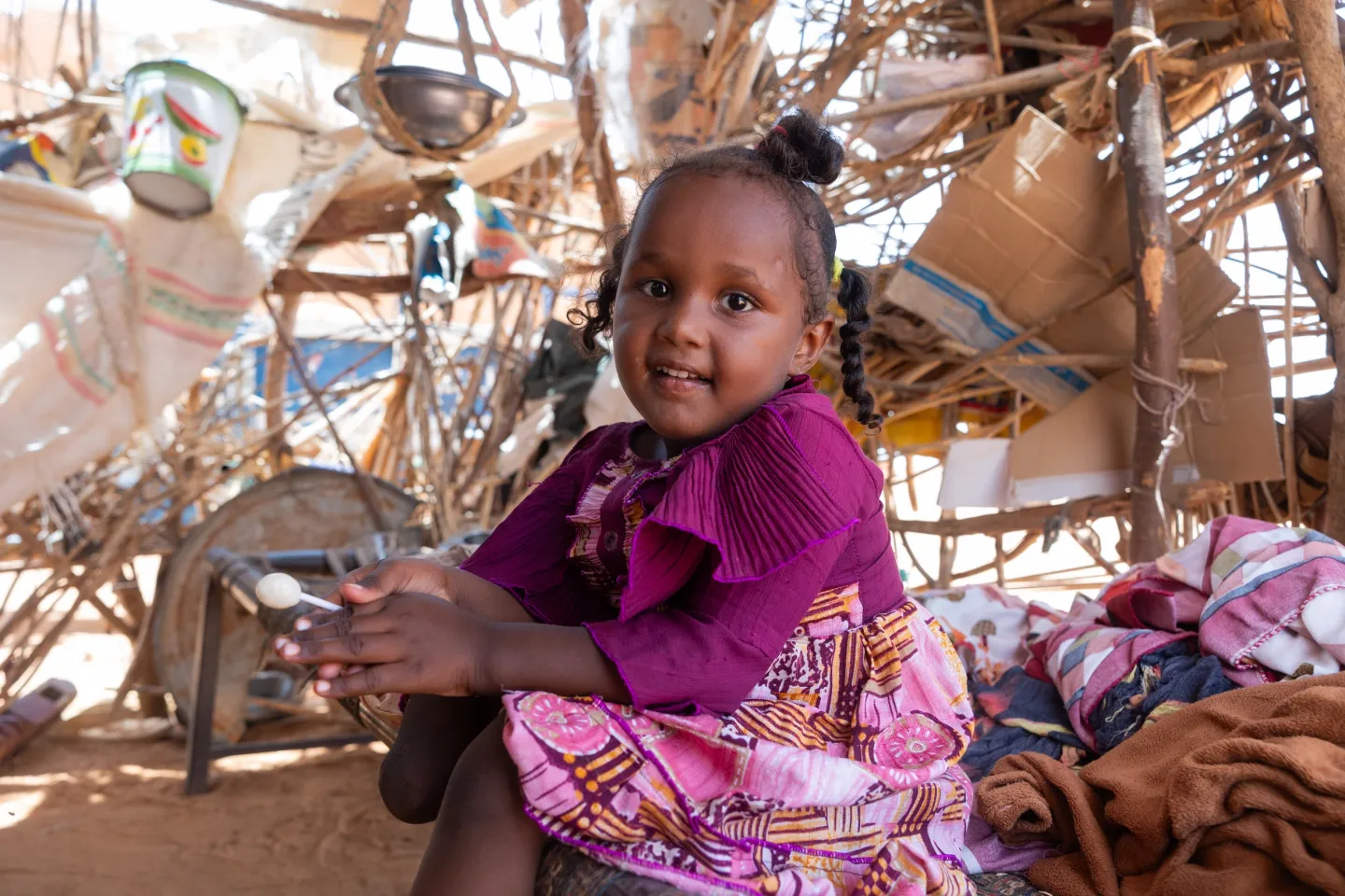 5-year-old Aisha sits in their home in Khartoum State. 