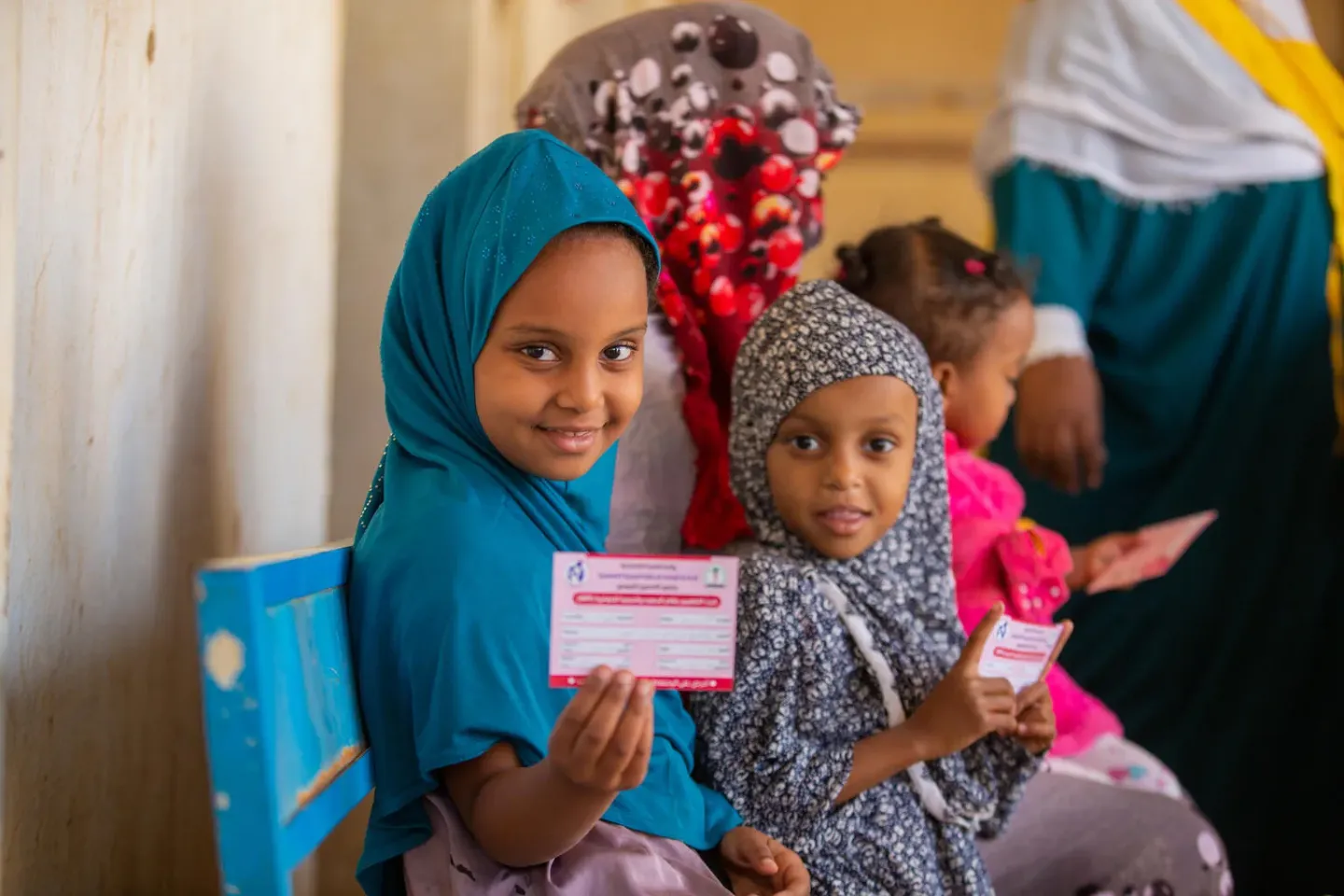 Children display their immunization cards after vaccination.