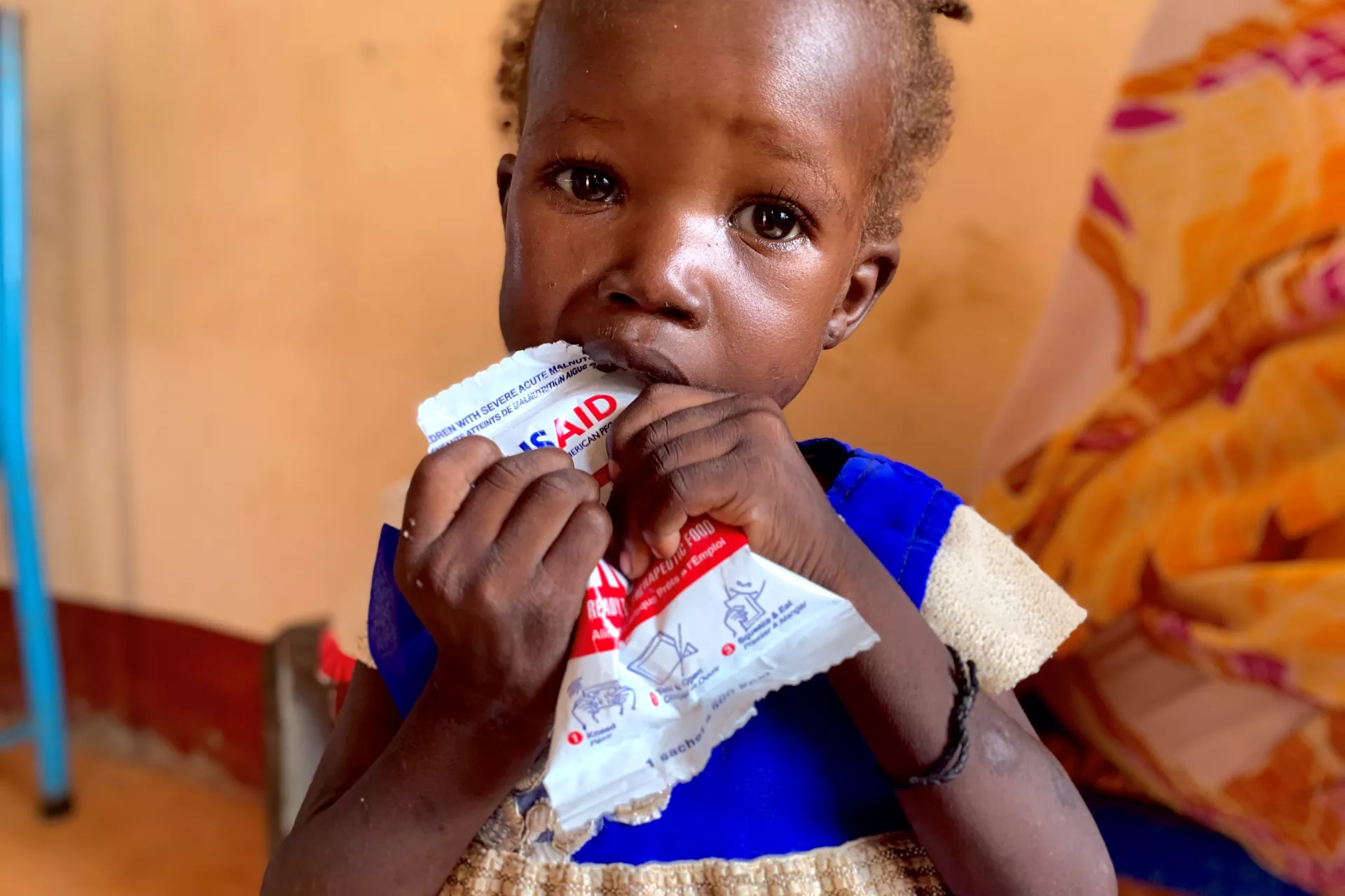Girl eats nutritional paste with USAID logo