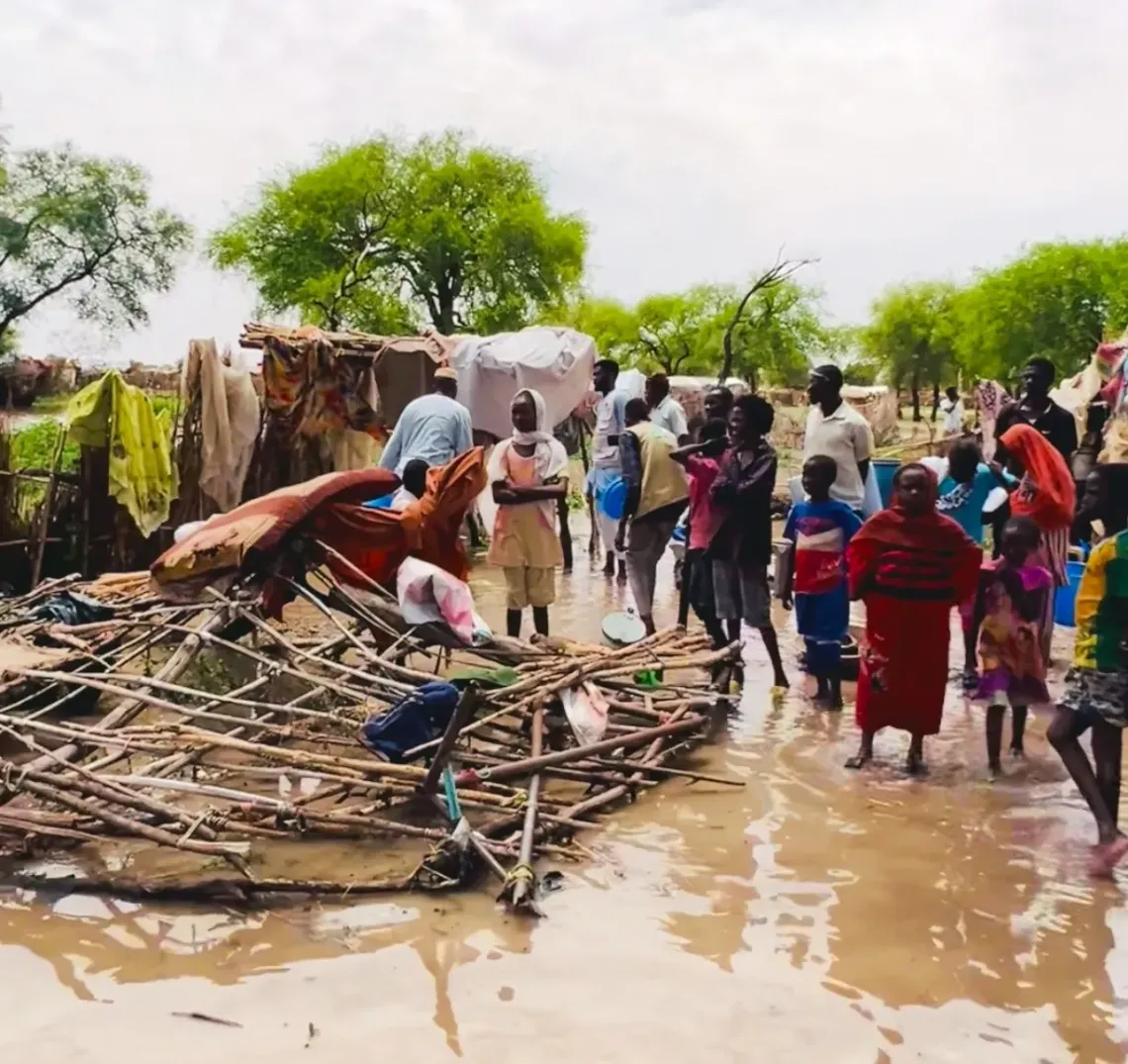 Children and families standing in stagnant water after heavy rains. 