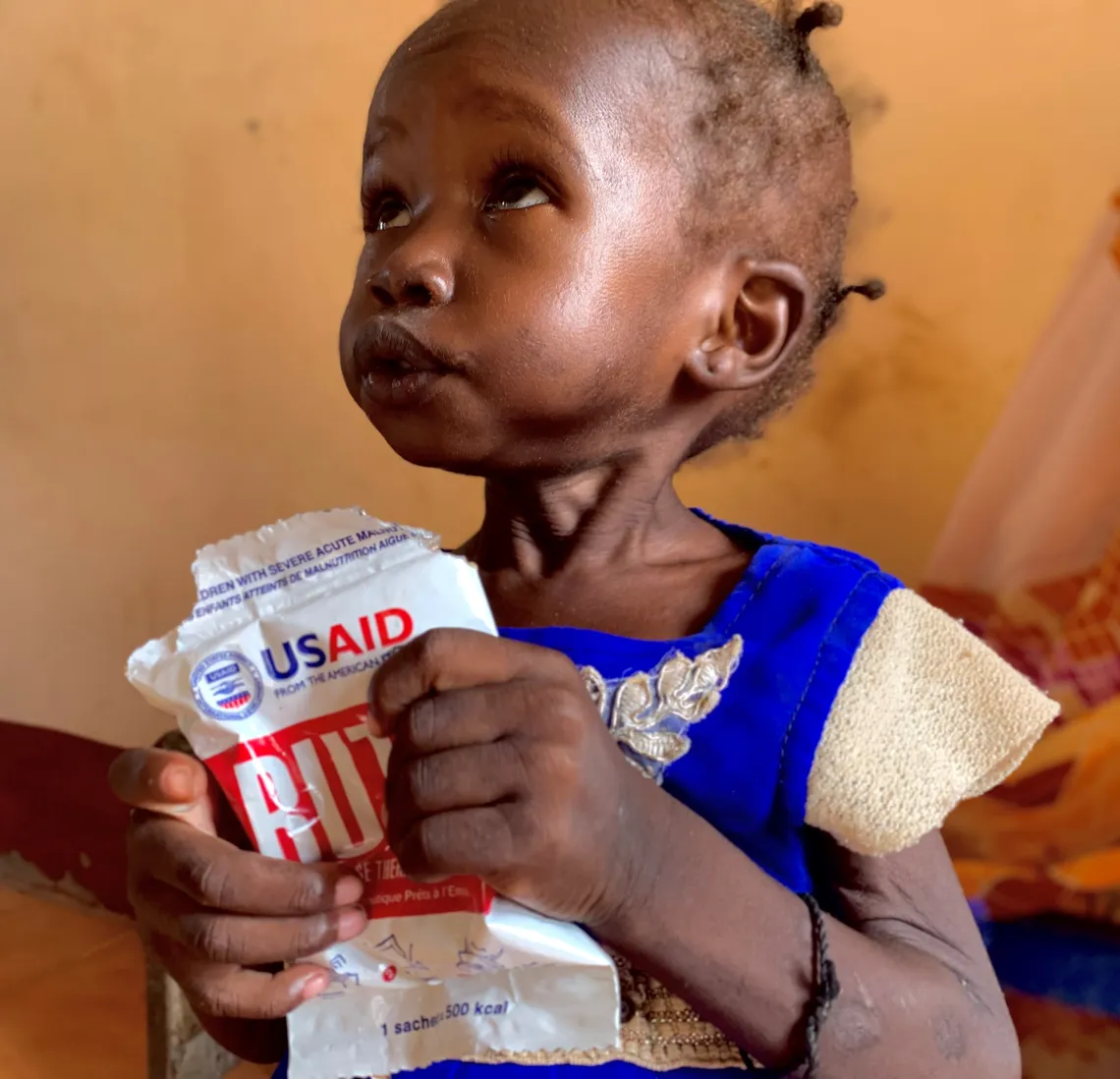 Girl holds RUTF with USAID logo