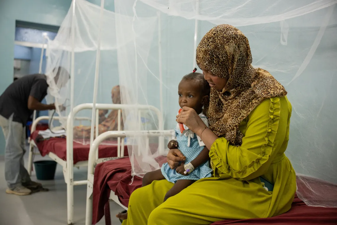 Wasila feeds her 18‑month‑old daughter, Seleen, who is suffering from severe acute malnutrition, with ready-to-use therapeutic food (RUTF) at the stabilization centre of Albuluk Hospital, Khartoum State.