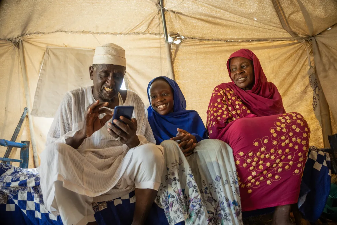 14-year-old Mariam enjoys a light moment with her grandparents, now her guardians in their temporary home in Goaz Salam internally displaced persons (IDP) Camp in Kosti, White Nile State.