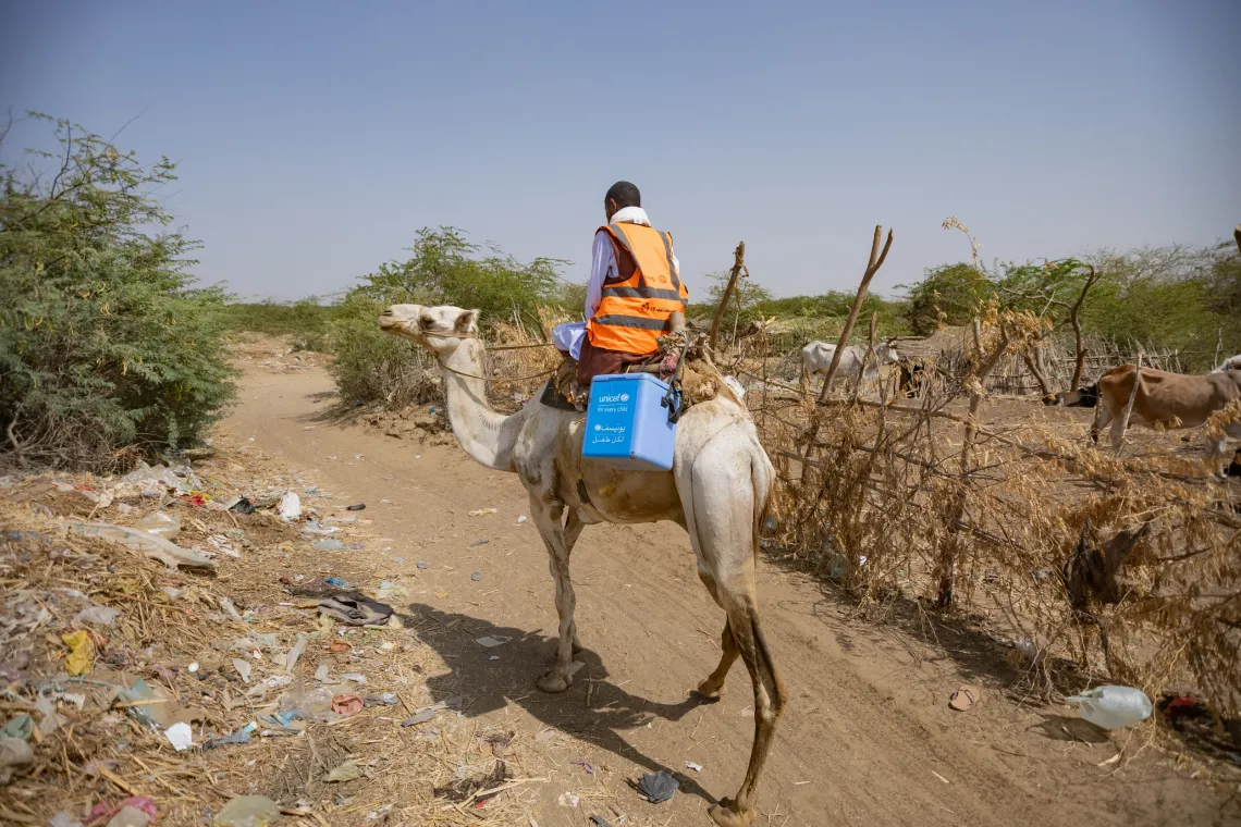 A vaccinator rides on a camel to reach children with vaccines during a camapign.