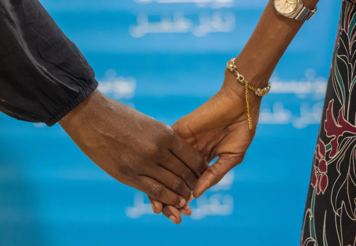 A social worker holds a child's hand during a counselling session.
