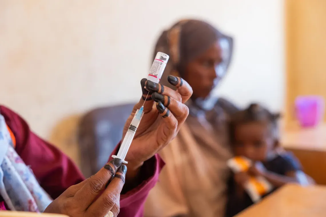 A health worker prepares vaccines before vaccinating a child