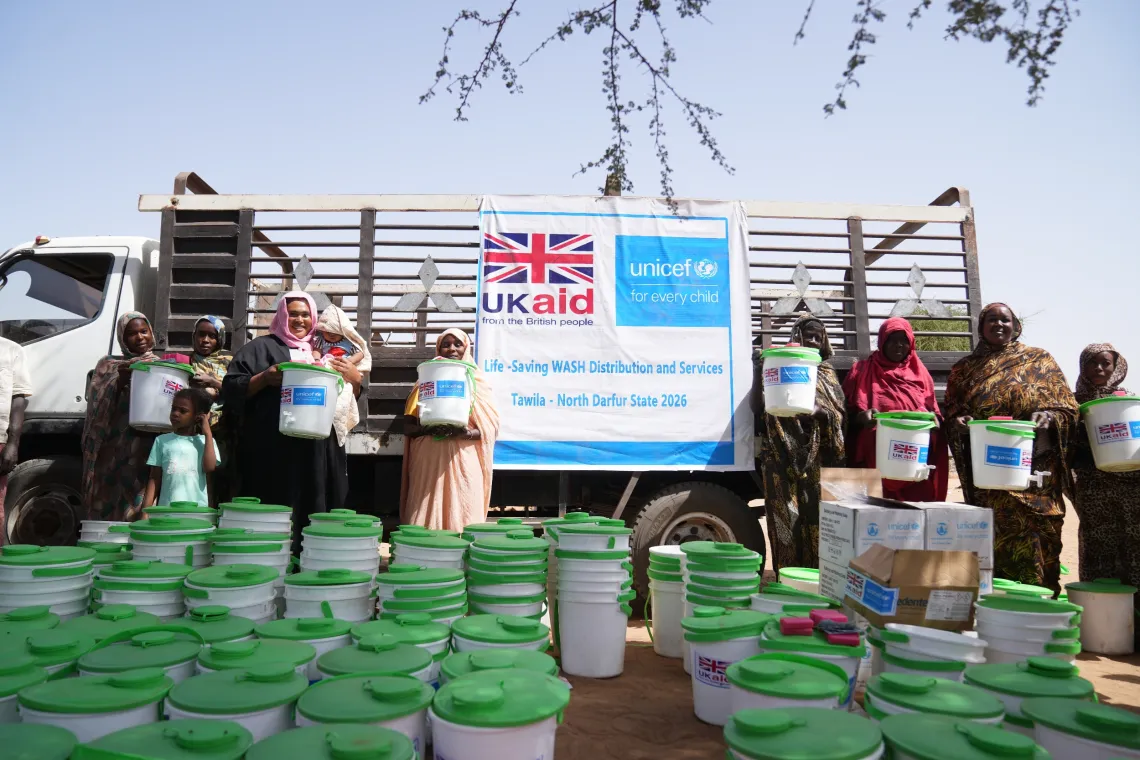 Women, caregivers and children receive water containers and soap at a distribution point in Daba Naira camp in Tawila, North Darfur.
