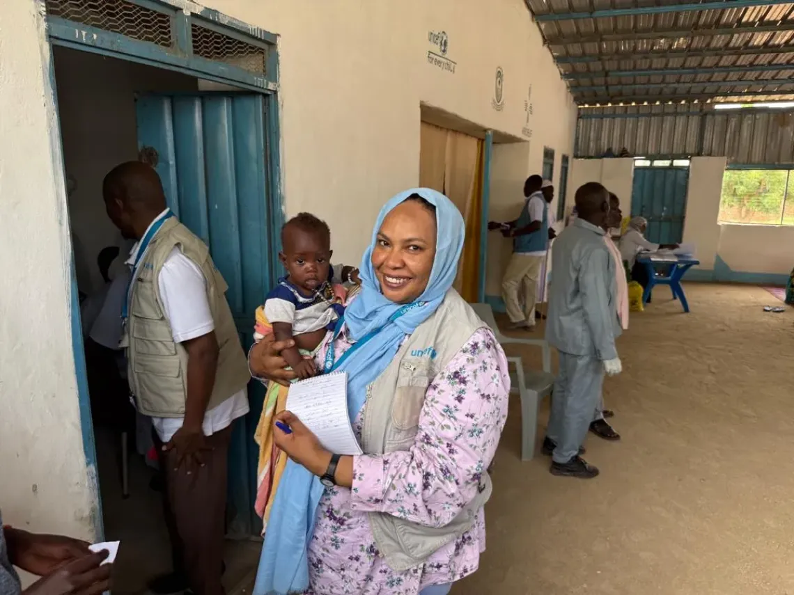 Hind Elbaqir, UNICEF Health Officer carries a child during a field mission.