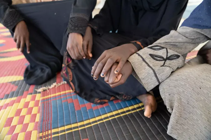 Sudan. Three girls hold hands at a child-friendly space