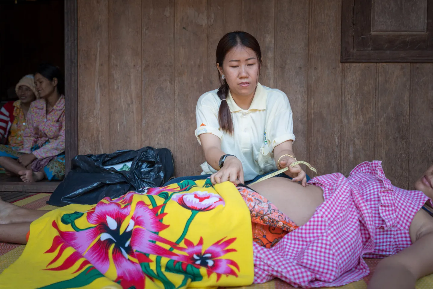 A secondary midwife at Sambo Health Centre, conducting a prenatal check-up for a pregnant woman in the village