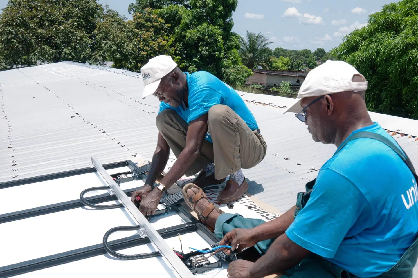 UNICEF staff on a rooftop installing solar refrigerators