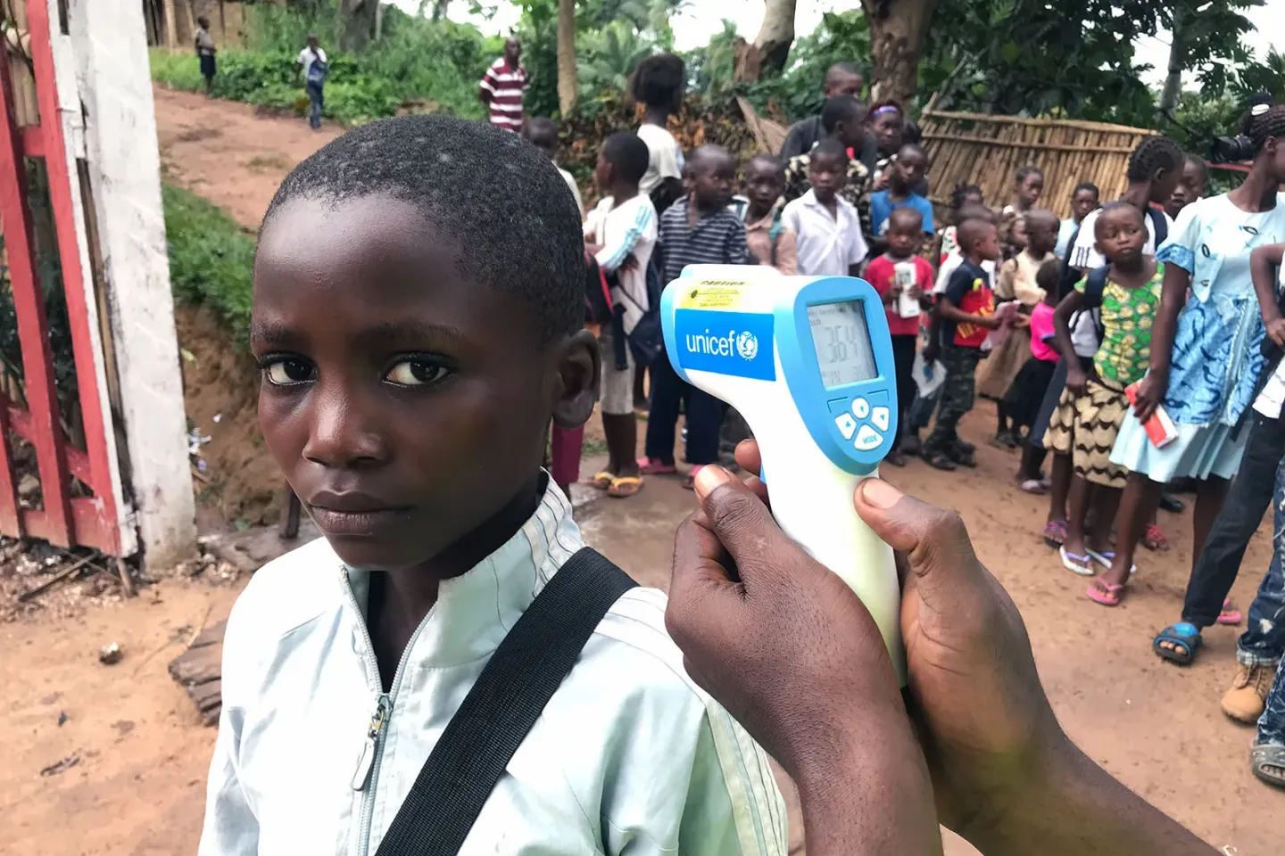 A schoolboy has his temperature screened with an infrared thermometer that has the UNICEF logo print on. 