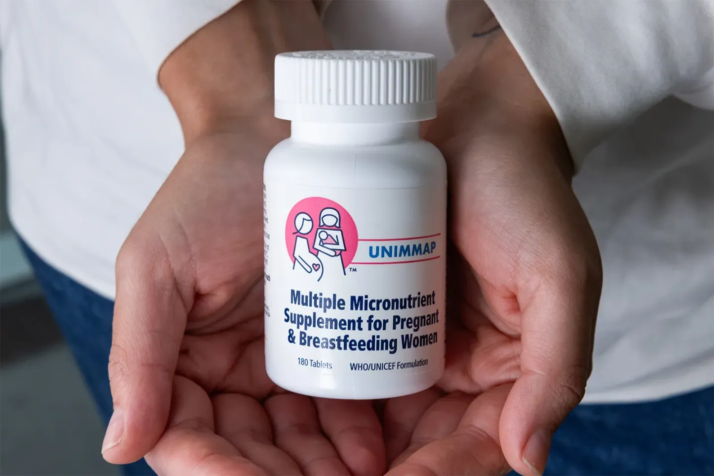 Two hands holding a bottle of Multiple Micronutrient Supplementation (MMS).
