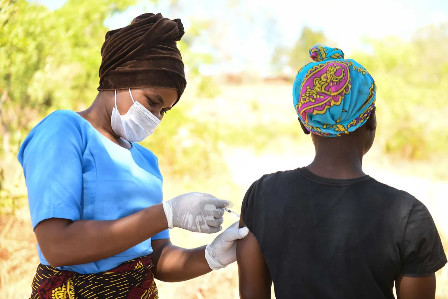 A health worker wearing a mask administers a COVID-19 vaccine in a resident at the Chiwinga Village in Kasungu District, Central Malawi on Tuesday, 14 December 2021. 