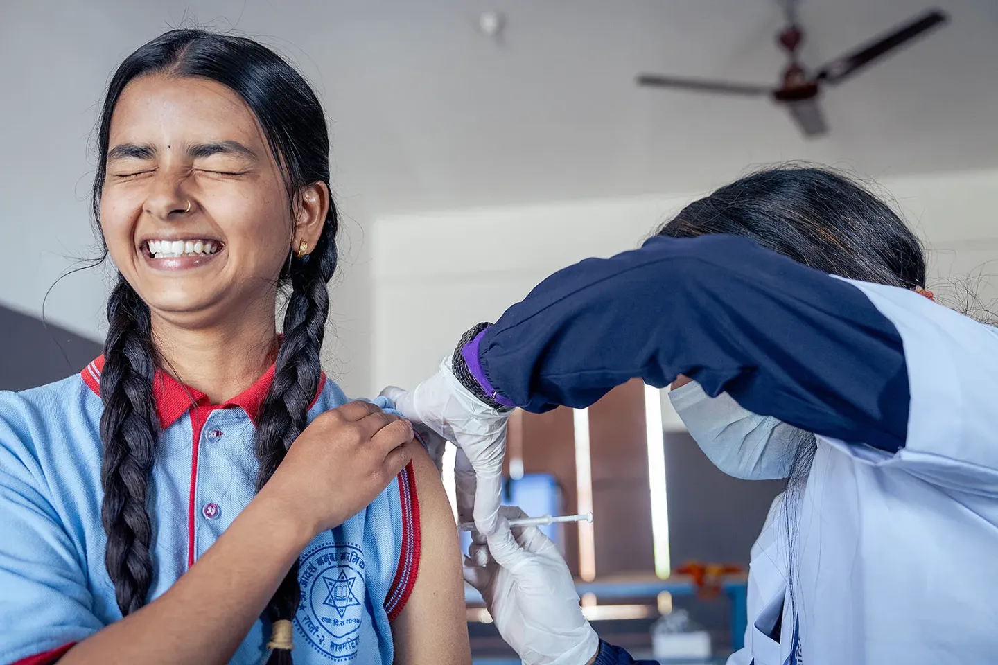 Teenage girl receiving a vaccination in her left arm, showing a mix of enjoyment and apprehension.