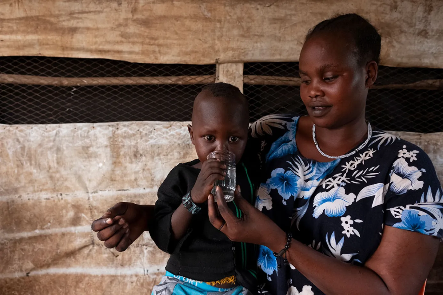 Mom gives her child clean water that has been pumped from the purification plant to the IDP camp.