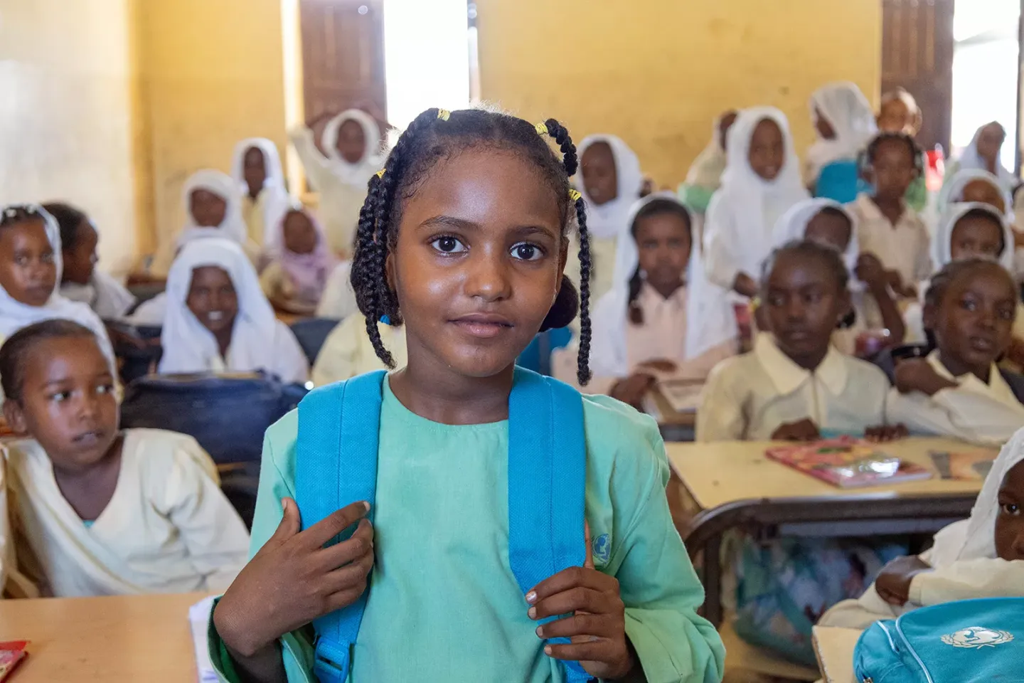 Wisam poses for a photo in the classroom with her UNICEF-branded backpack