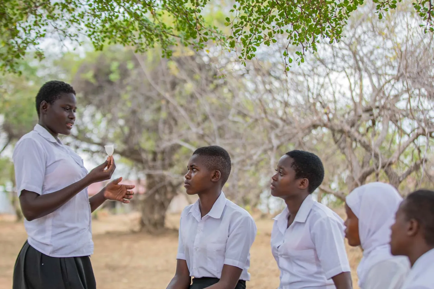 A volunteer demonstrates to her peers how to correctly use a menstrual cup